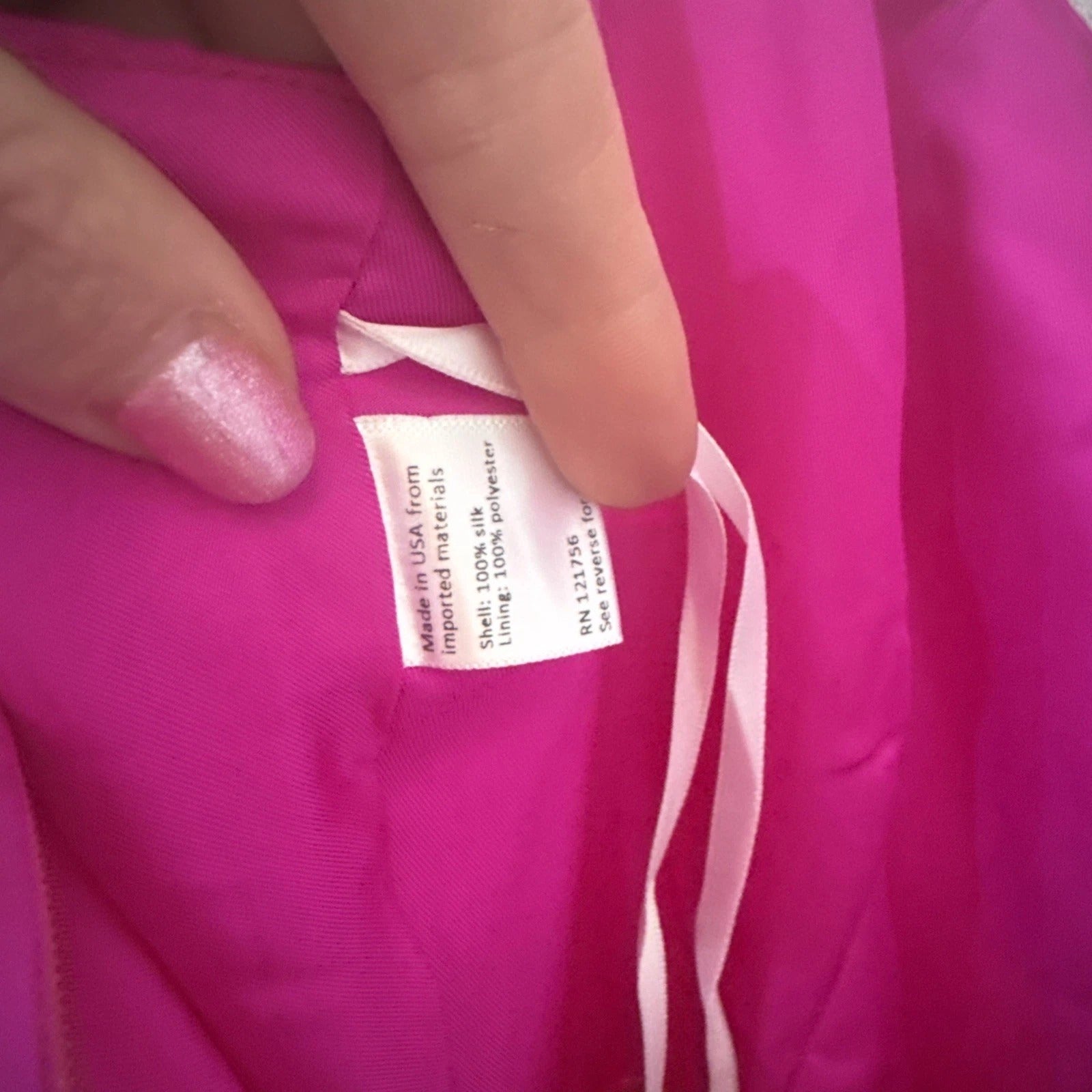 Close-up of a pink garment with a label held by fingers.