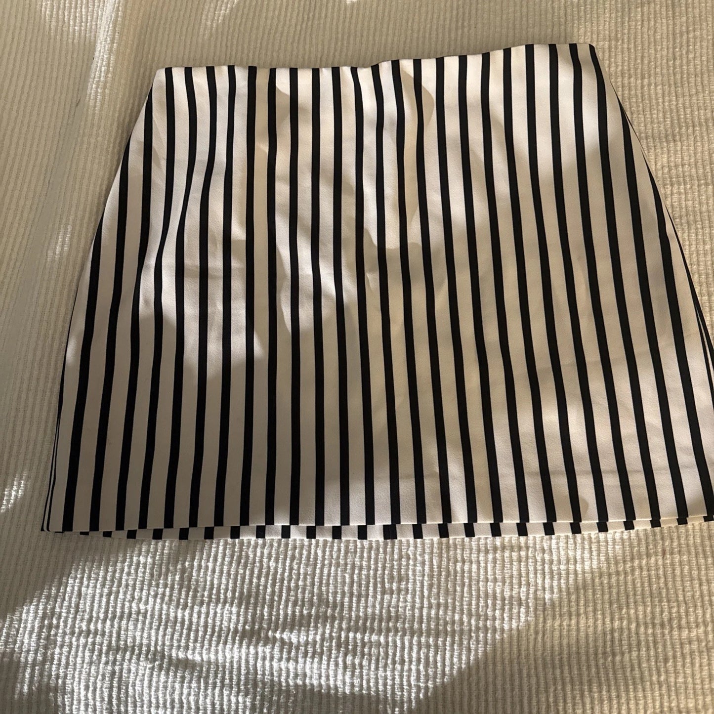 Black and white striped fabric on a textured beige surface