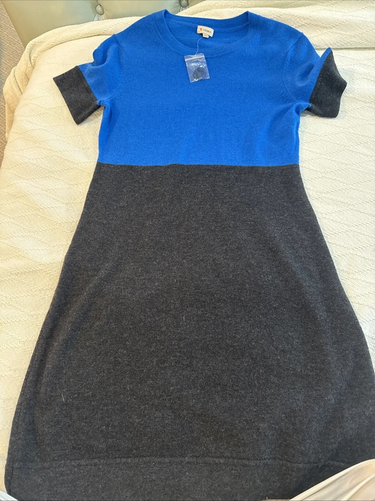 Two-tone blue and gray dress on a bed with a tag.