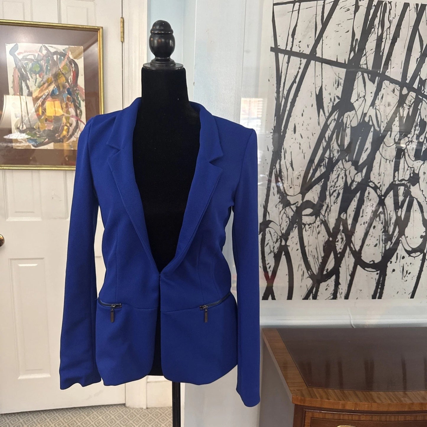 Blue blazer on a mannequin against a wall with abstract art