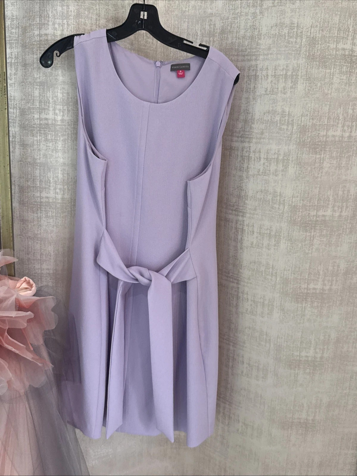 Lavender dress on a hanger against a textured wall