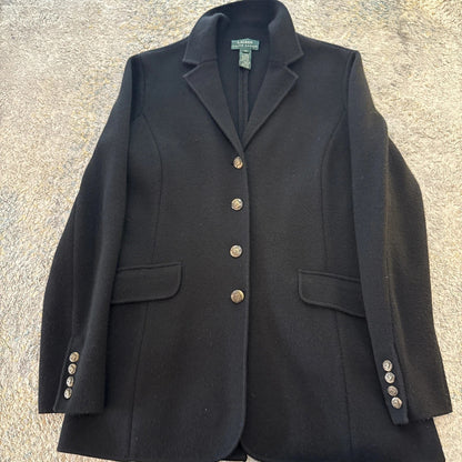Black blazer with gold buttons on a textured surface