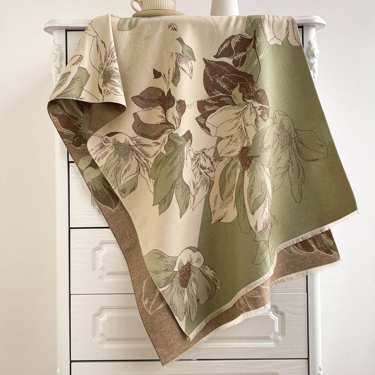 Sage and cream floral scarf draped on dresser at Dover Grace Boutique in Watkinsville, Georgia.