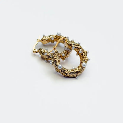Chunky textured gold-tone hoop earrings studded with small white pearls on a white background.