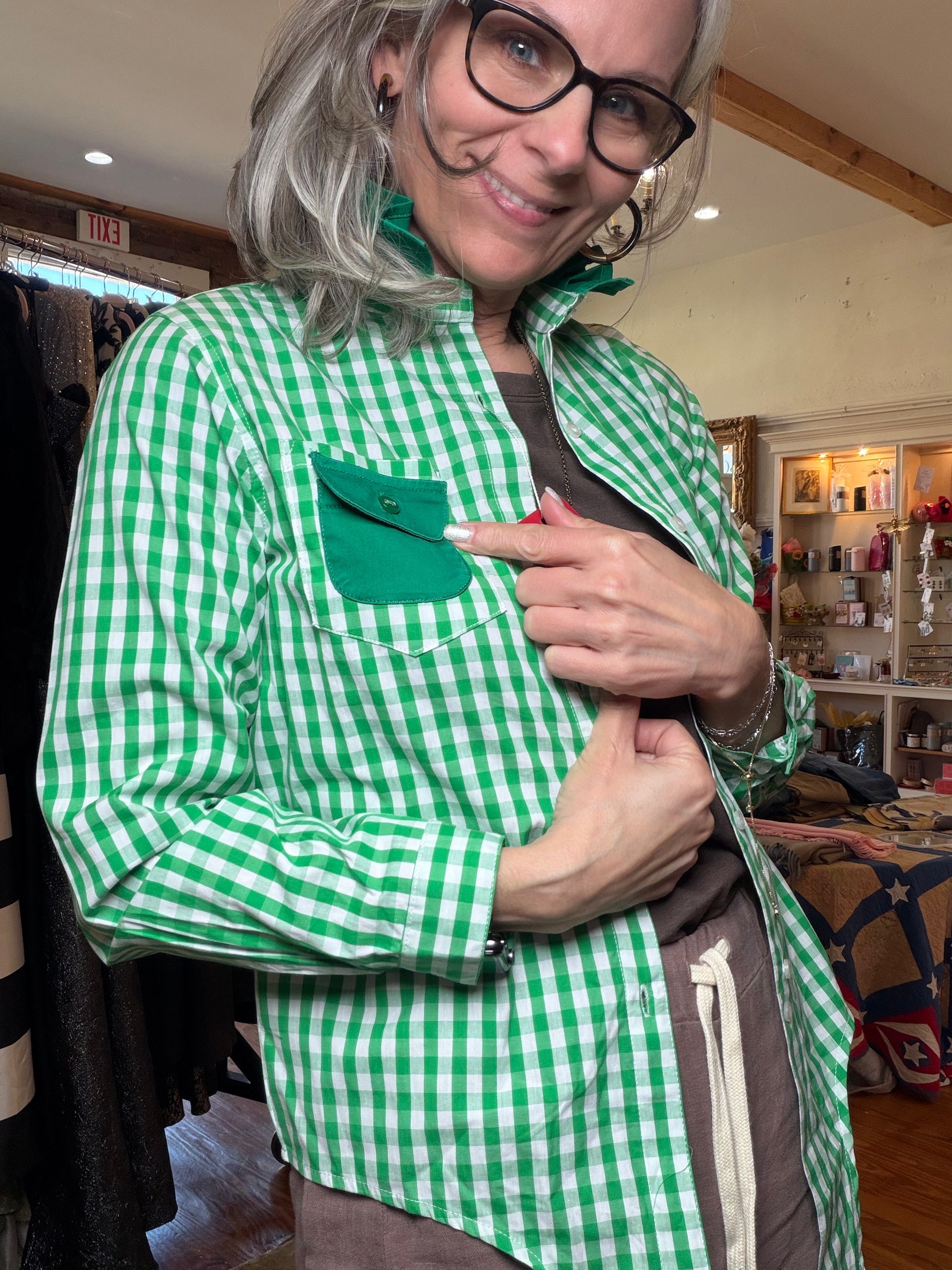 Side view of a green gingham shirt showing the long sleeve and contrast green pocket.