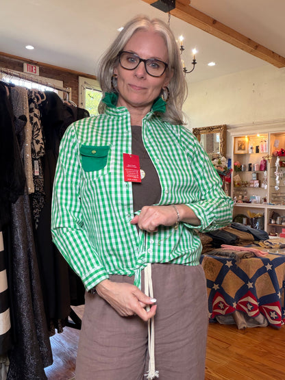 Green gingham shirt worn open over a taupe outfit with the front hem tied at the waist.